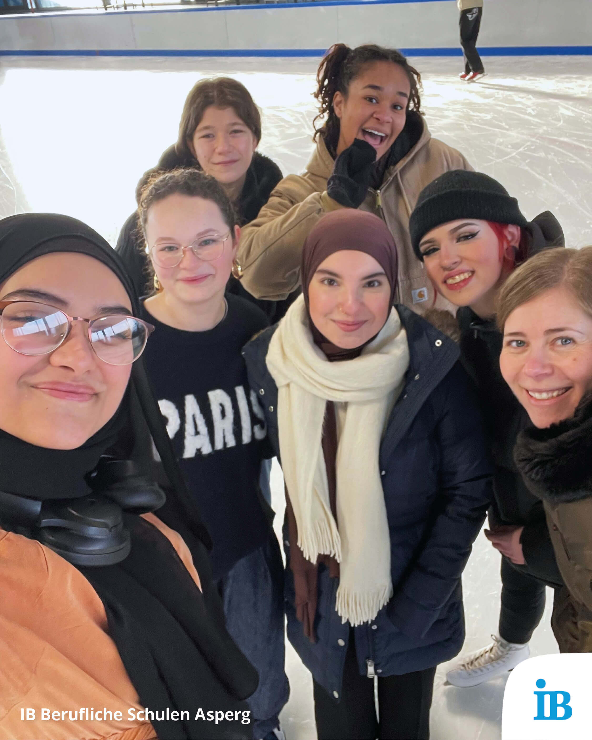 Eine Gruppe fröhlicher Menschen posiert auf einer Eisbahn beim Wintersporttag für ein gemeinsames Foto.