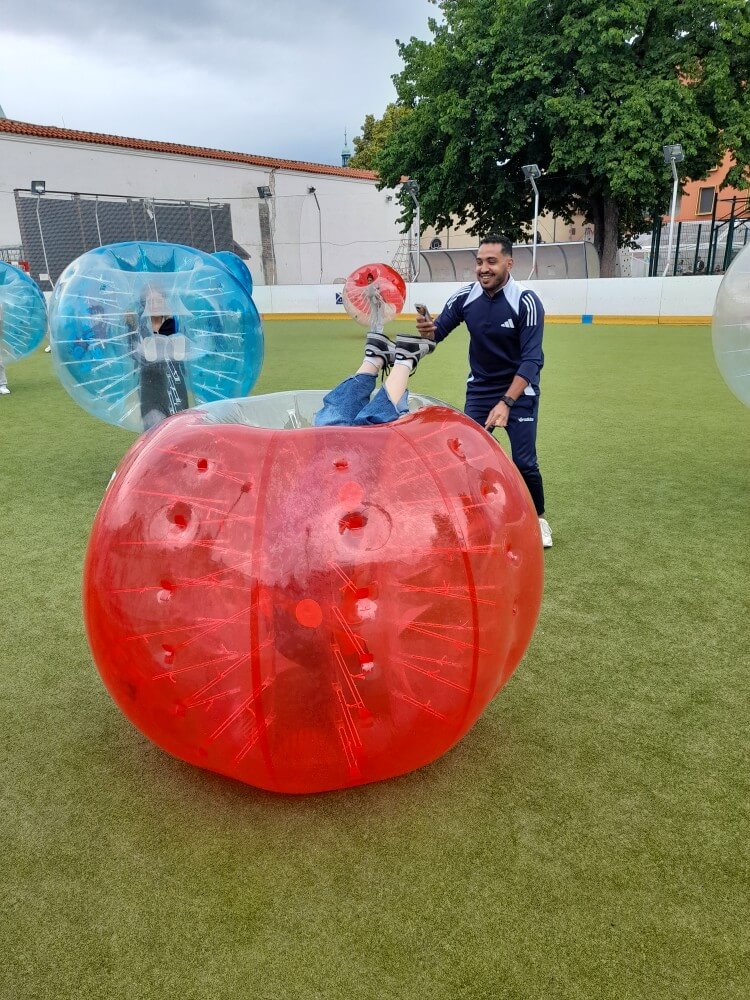 Ein Spieler in einer roten Bubble-Ball-Kugel wird von einem Freund auf dem Spielfeld gefilmt.